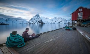 Man sitting by the water with a PC in his lap