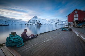 Man sitting by the water with a PC in his lap