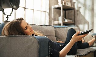 Relaxed woman lying on sofa and watching tv