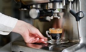 Hand making cup of coffee on machine