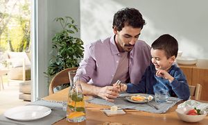 Man and child sitting at a dinner table eating