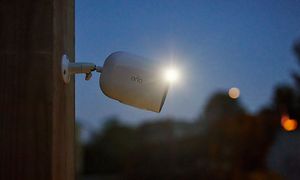 Arlo Go V2 sikkerhetskamera festet til en vegg utendørs om natten