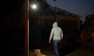 Et Arlo Go V2 Sikkerhetskamera som er festet til veggen og lyser på en mann med hettegenser