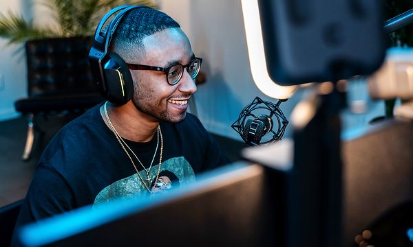 mann sitter foran to PC-skjermer med mikrofon og lys fra Logitech