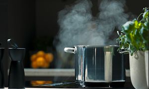 gryte med damp står under en platetopp med vifte