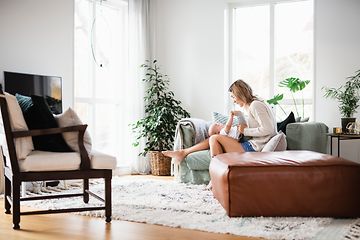 Woman and baby sitting on a couch in the living room