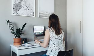 Kvinne jobber på laptop på lite hjemmekontor