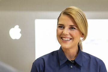 Smilende Elkjøp-ansatt ved siden av en Apple-logo
