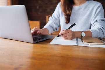  Forretningskvinne jobber på den bærbare datamaskinen sin og skriver i en notatbok