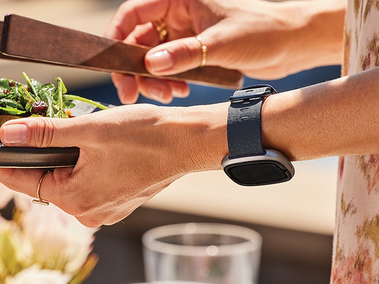 Woman with Fitbit smartwatch with a plate of salad