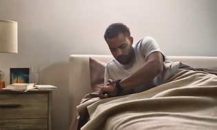Man in bed with Venu 2 on his arm