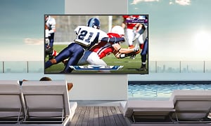 En Samsung The Terrace TV som viser en amerikansk fotballkamp utendors med sterk sol i bakgrunnen
