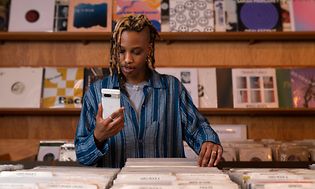 Man in a record store looks at a Google Pixel 7