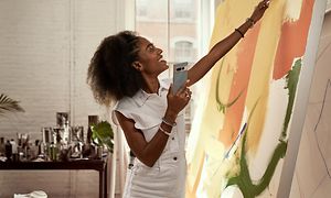 Woman painting and holding a Google Pixel 7 Pro