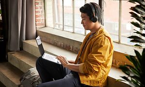 En gutt sitter i nærheten av et vindu med sin HP X360 Chromebook