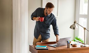 Mann med kaffekopp som berører Samsung Chromebook 4 på skrivebordet