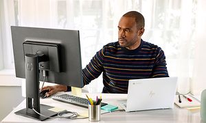 En mann ved et skrivebordet ser på en skjerm og jobber med HP-elite Chromebooken sin