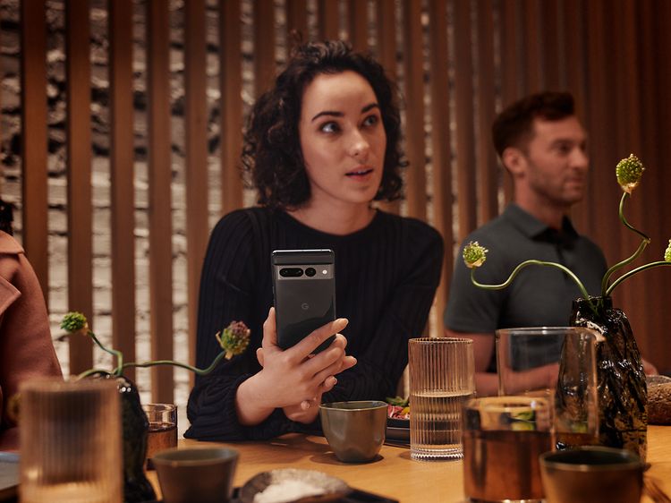 Woman in restaurant holding Pixel phone