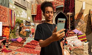 Mann som står på et marokkansk teppemarked og ser på Google Pixel 7 Pro