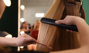 Long hair being styled with hair straightener by hair dresser