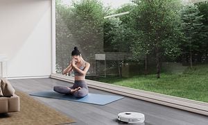 DEEBOT T9 OZMO Pro rengjøring mens en kvinne konsentrerer seg om yoga