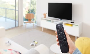 Logitech-Hand holding TV remote in living room
