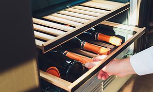 Man taking wine bottles from a wine cooler