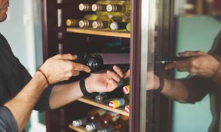 A waiter taking wine bottles from a wine cooler