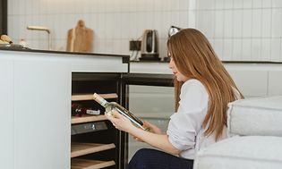 A woman choosing a bottle of wine from a wine cooler