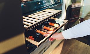 Man taking a wine bottle from a wine cooler