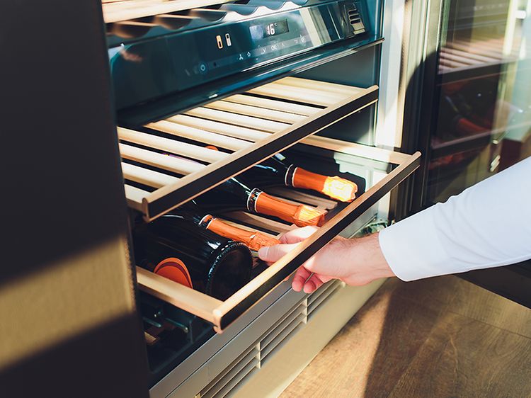 Man taking wine bottles from a wine cooler