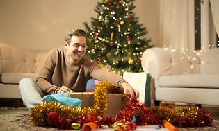 Man opening presents in front of a Christmas tree