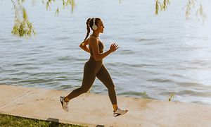 Woman running with headset waterside