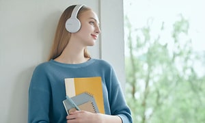 Woman with Sonys headphones holding notebooks