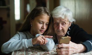 Eldre kvinne og ung jente som ser på smarttelefonen sammen