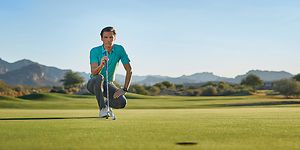 Mannlig golfspiller på golfbane med en Garmin Approach golfklokke på armen
