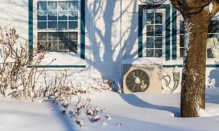 SDA - Heat pump - Outdoor unit in the snow in front of a house