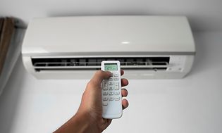 SDA - Heat pump - Man's hand holding remote controller pointed towards heat pump