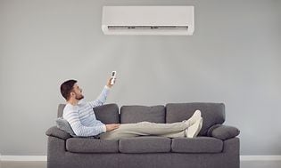 Man lying on couch, controlling a heat pump