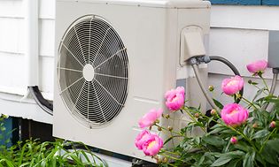 Air intake box mounted to a wall next to flowers