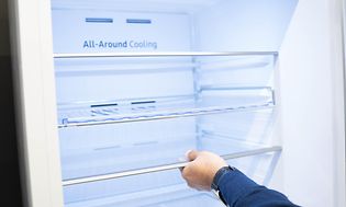 Man's hand adjusting the shelf on the interior of a fridge