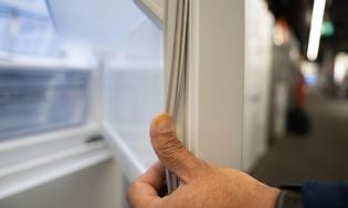 Man's hand bending rubber seal on fridge