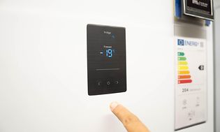 Man's finger pointing at temperature controls on a freezer