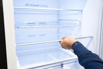 Man's hand holding the shelf of a fridge