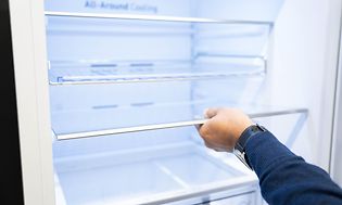 Man's hand holding the shelf of a fridge