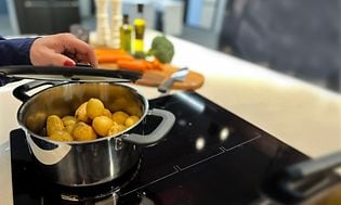 Hand closing the lid on a pot on a stove