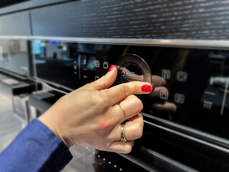 Hand adjusting the temperature dial of an oven