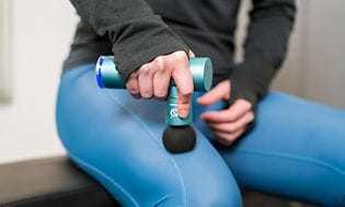SDA - Massage - Picture of a woman using a massage gun on her thigh