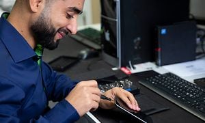 B2B - CS - Services - A smiling Elkjøp employee fixing an iPhone
