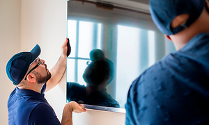 B2B - CS - Services - Two employees installing a TV on a wall